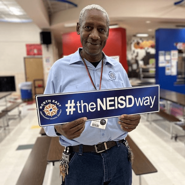 NEISD Woodstone Custodian Potter holding theNEISDWay sign