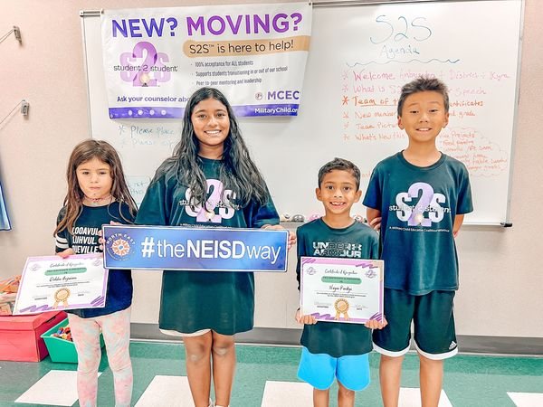 NEISD Hardy Oak students hold NEISD way sign