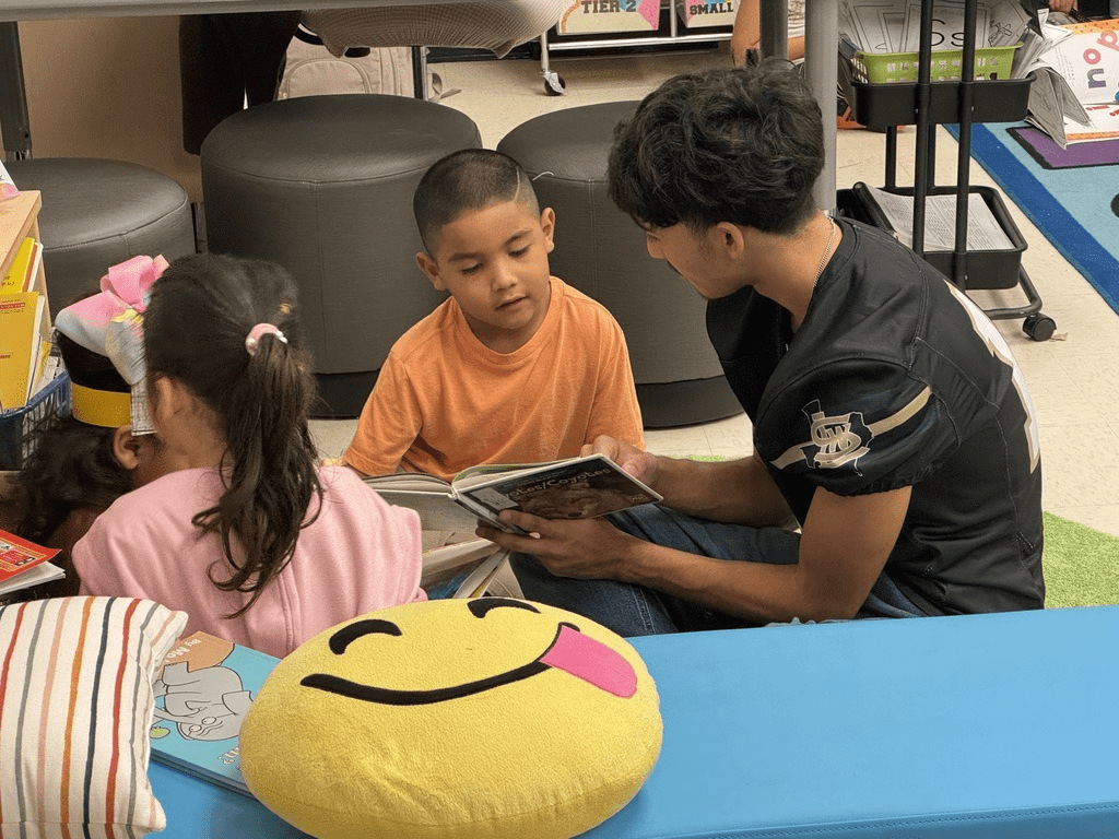 High school student reading with a young student