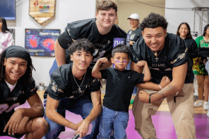 SW Legacy football players posing with elementary student